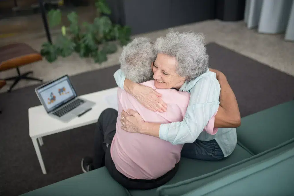 An elderly couple hugging each other on the sofa.