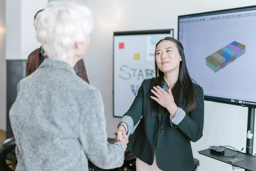 A female investor shaking hands with an old woman.