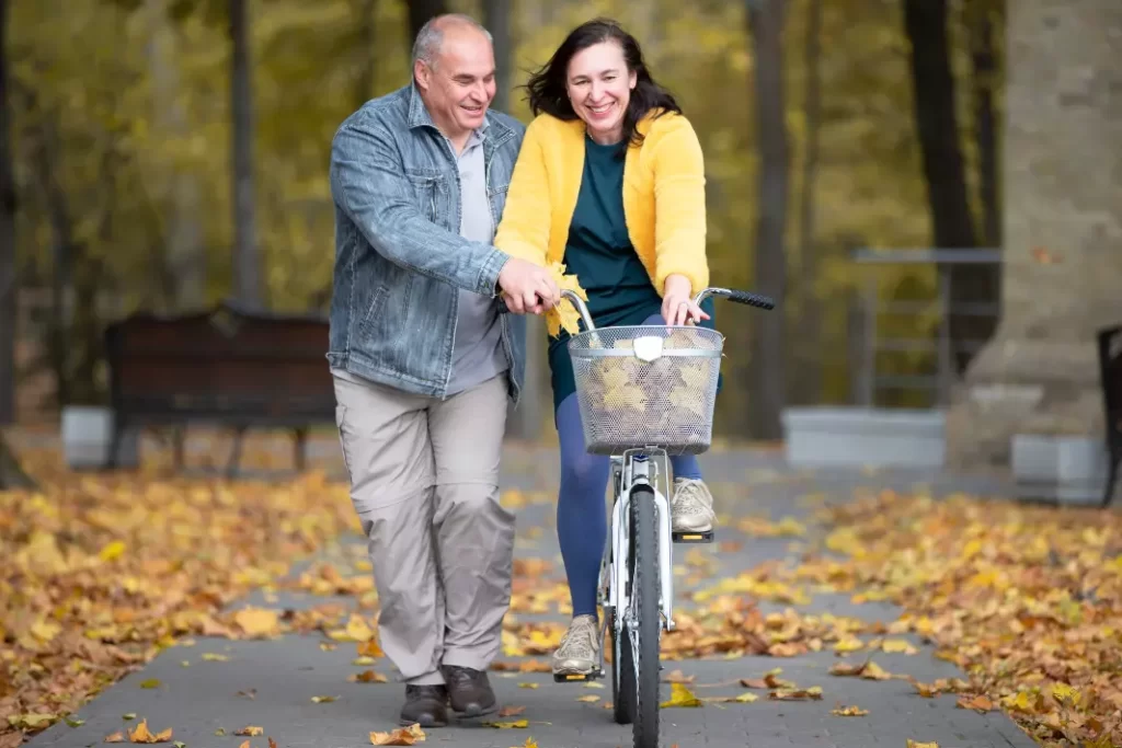 A husband teaching his wife how to bike.