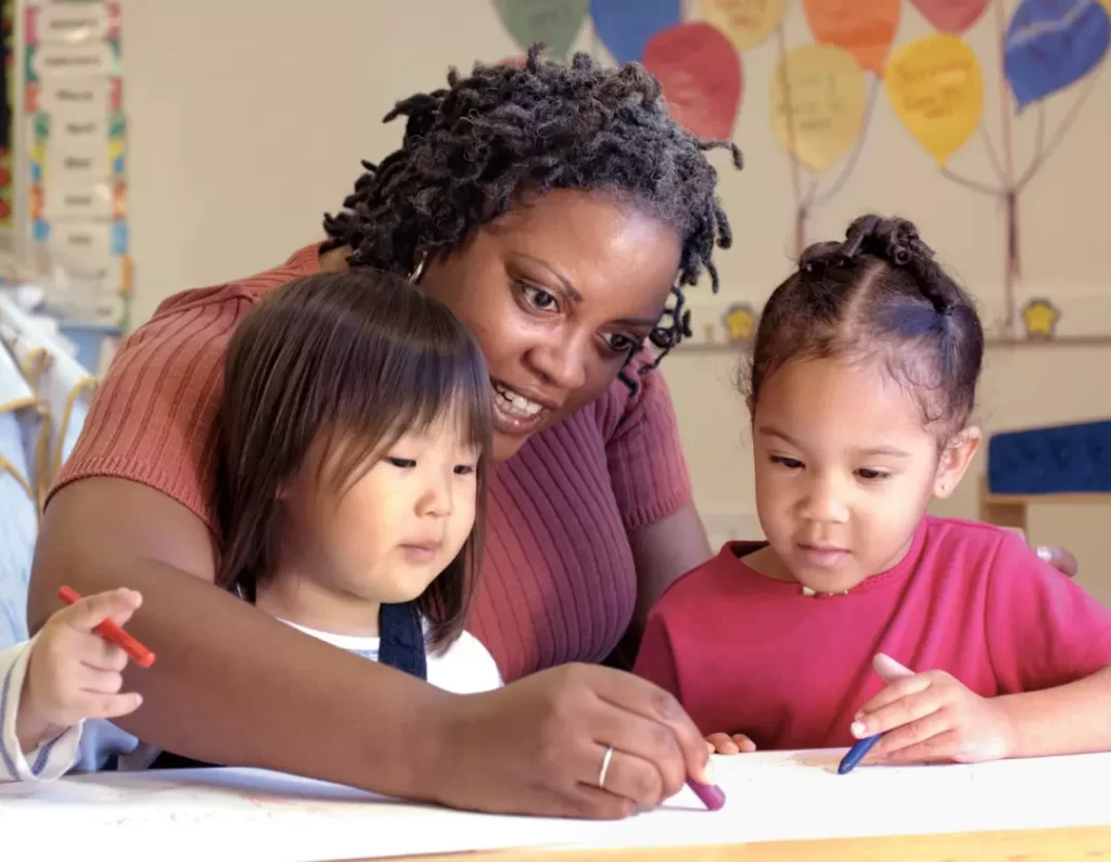 A teacher teaching her two little students how to color.