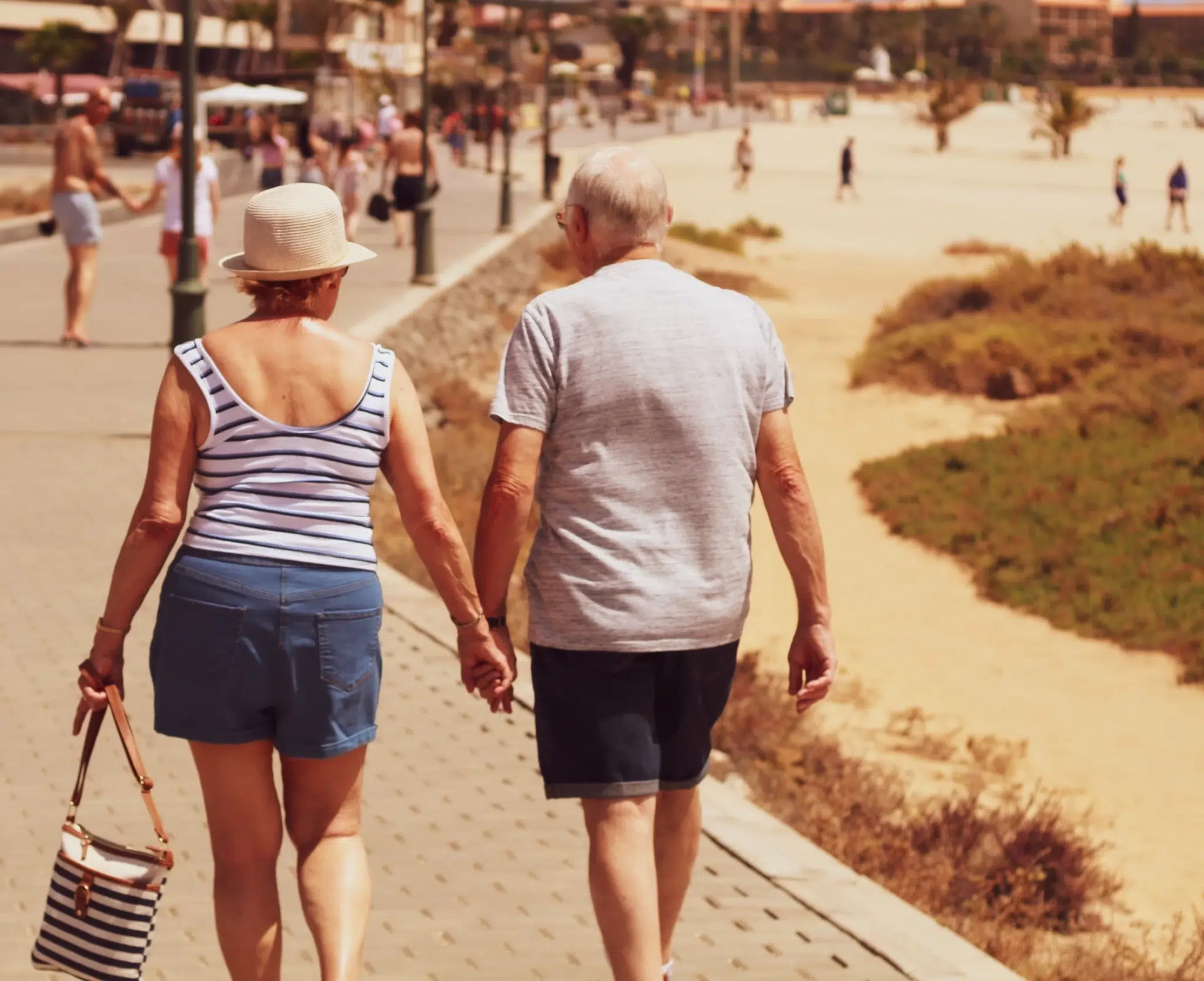 Elderly couple walking on the road while holding hands.