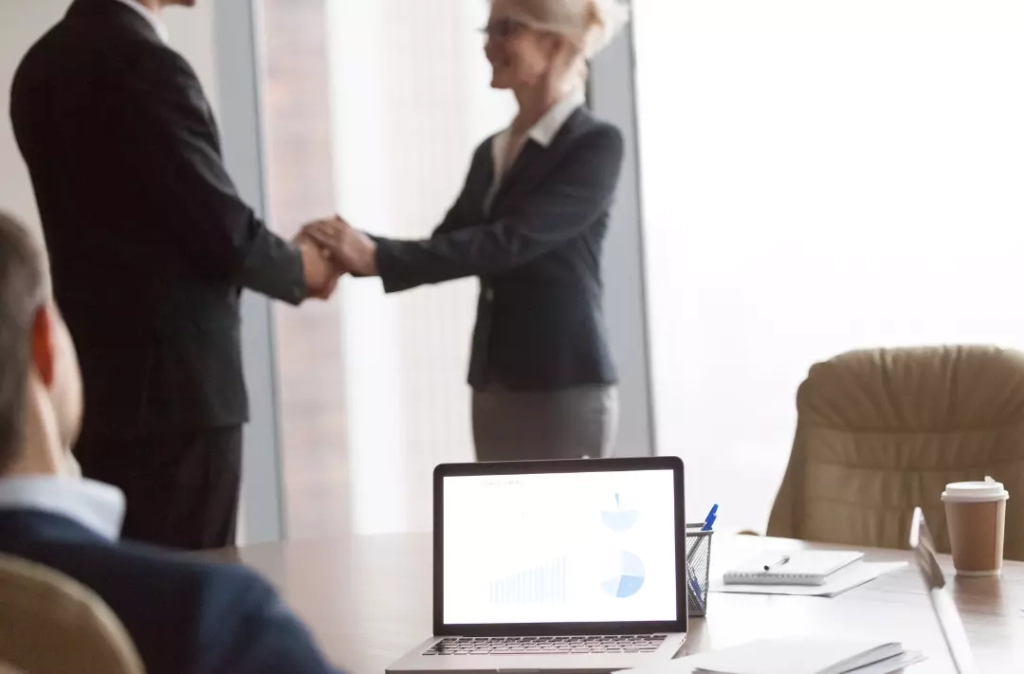 Man and woman in business attire having an agreement by shaking hands.
