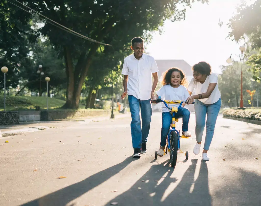 Parents teaching their child how to ride bicycle.