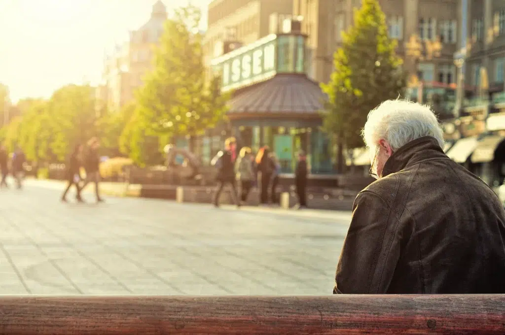 An old man sitting on wooden bench.