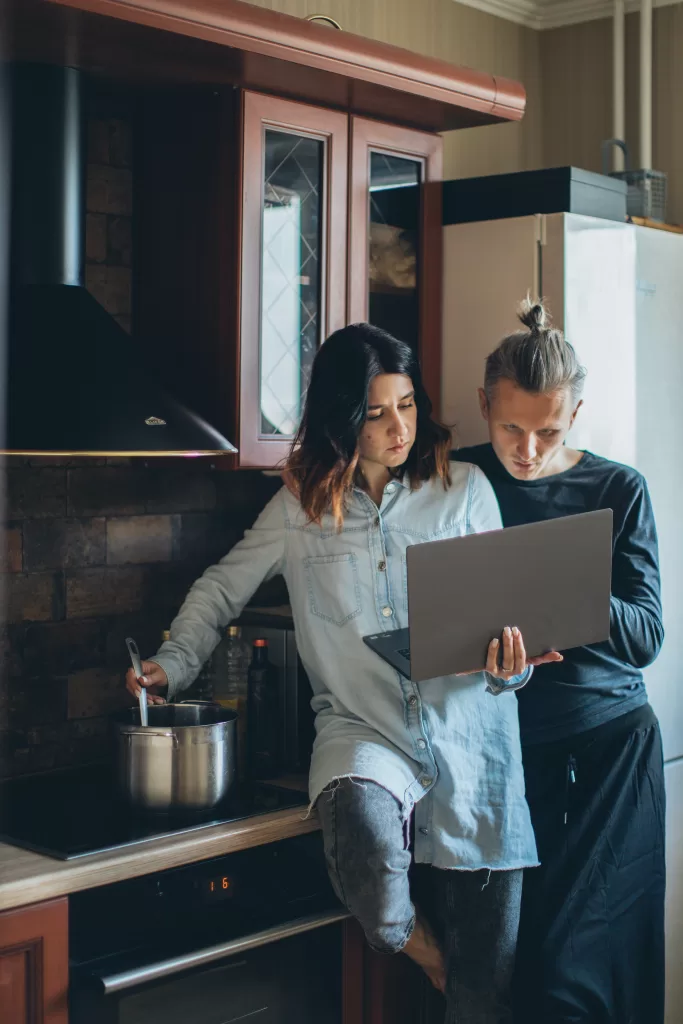 Couple using a laptop in the kitchen.