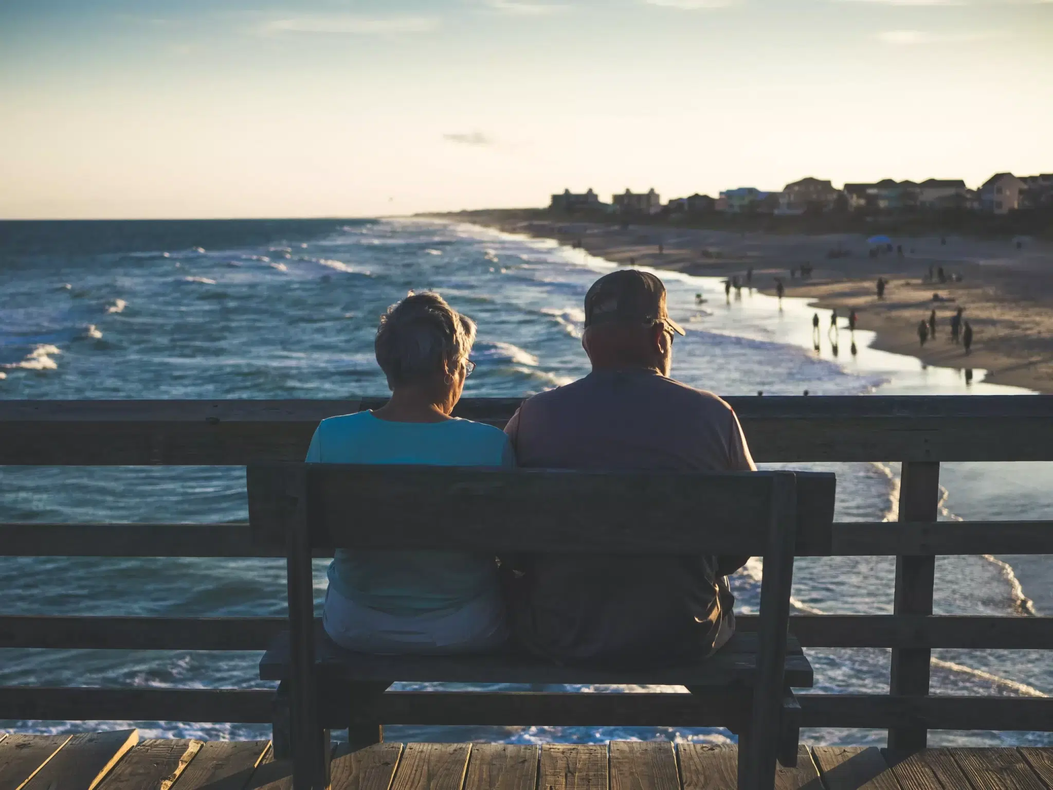 Couple sitting on a wooden chair overlooking the beach.