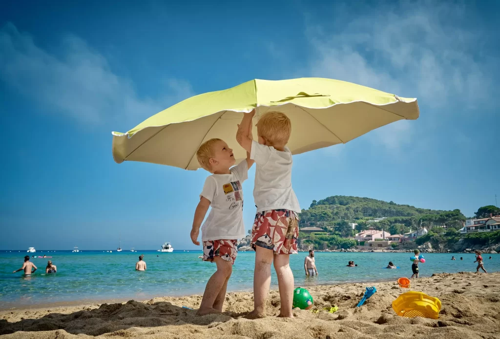 Two children setting up an umbrella on seashore.