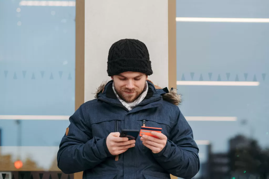 Happy man entering his credit card details on smartphone.
