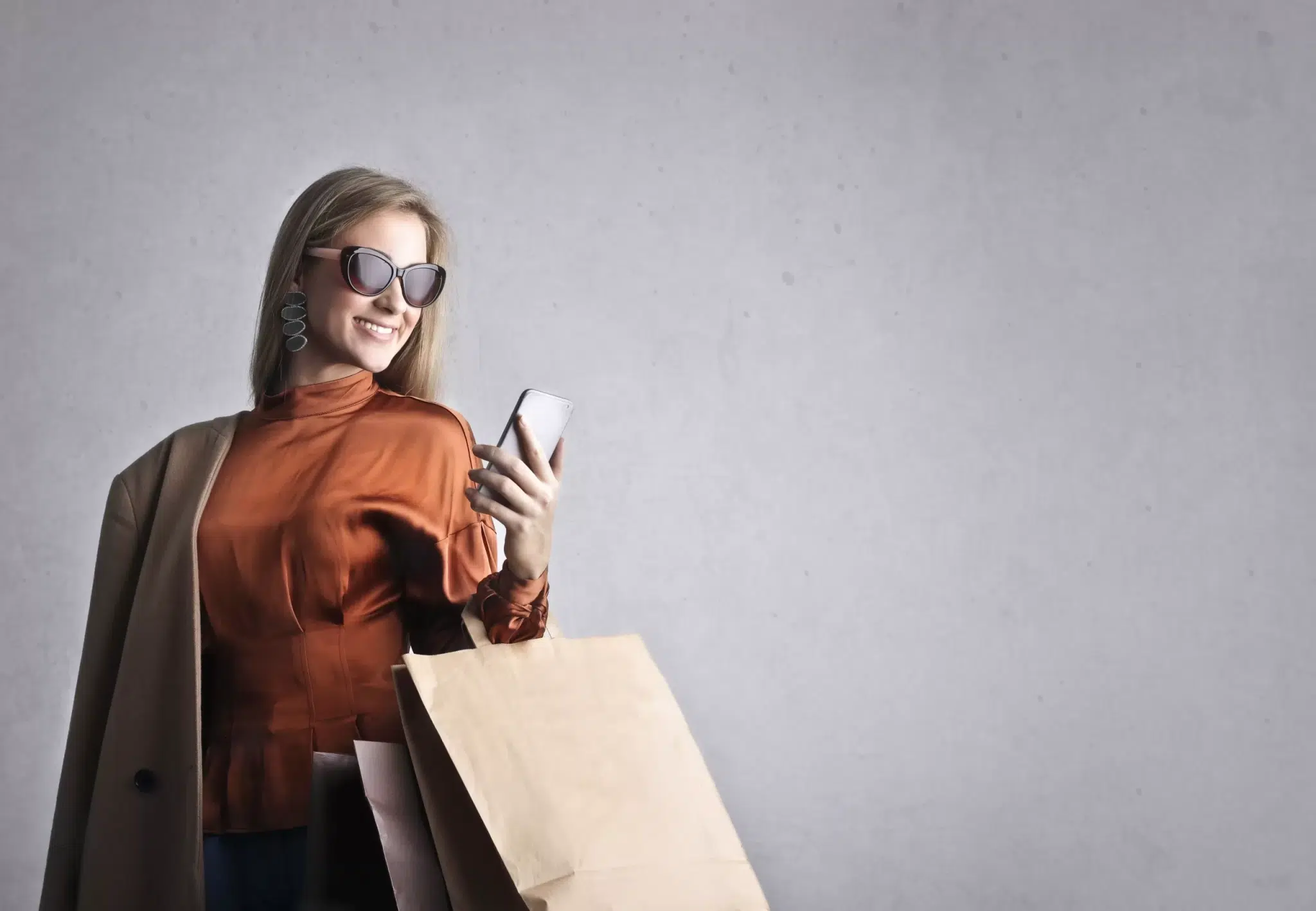 Woman went shopping wearing a sunglass and holding a phone.