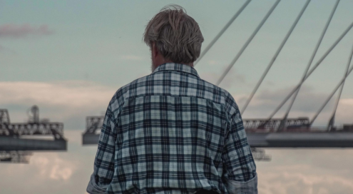 Back view of an old man facing a bridge.