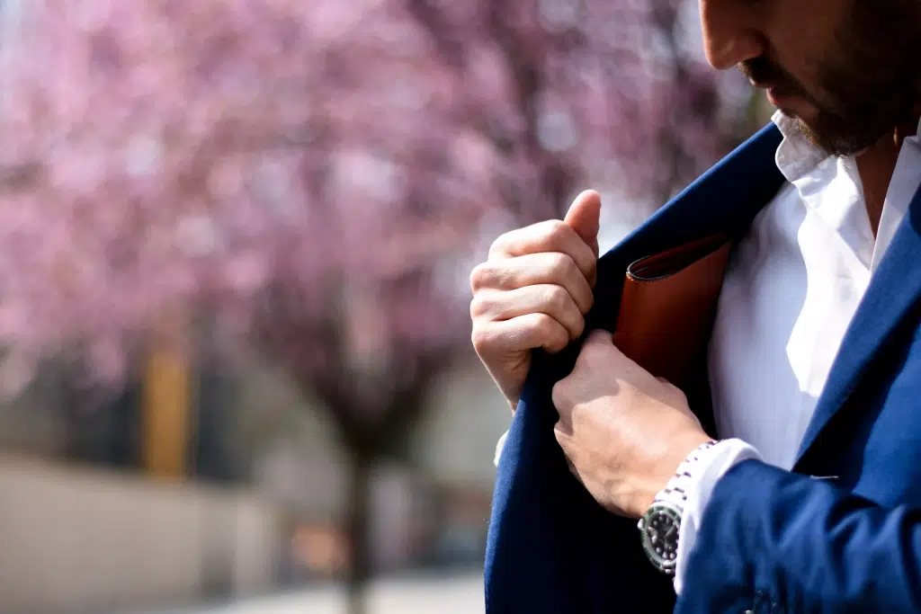 Man putting his wallet on his suit pocket.