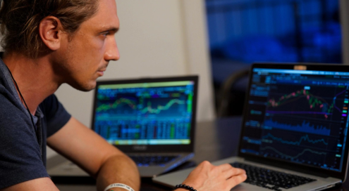 Man using laptop to monitor trading.