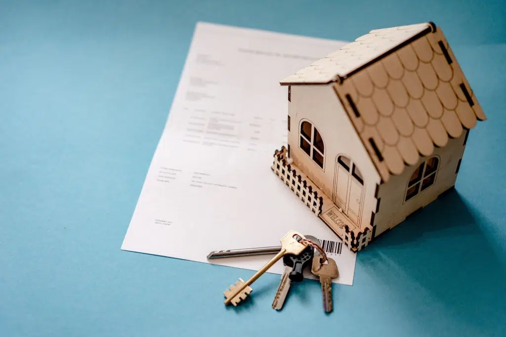 Miniature house with keys and paper.