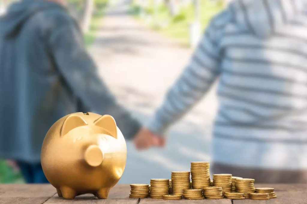Golden piggy bank with coins stacked beside two people holding hands.