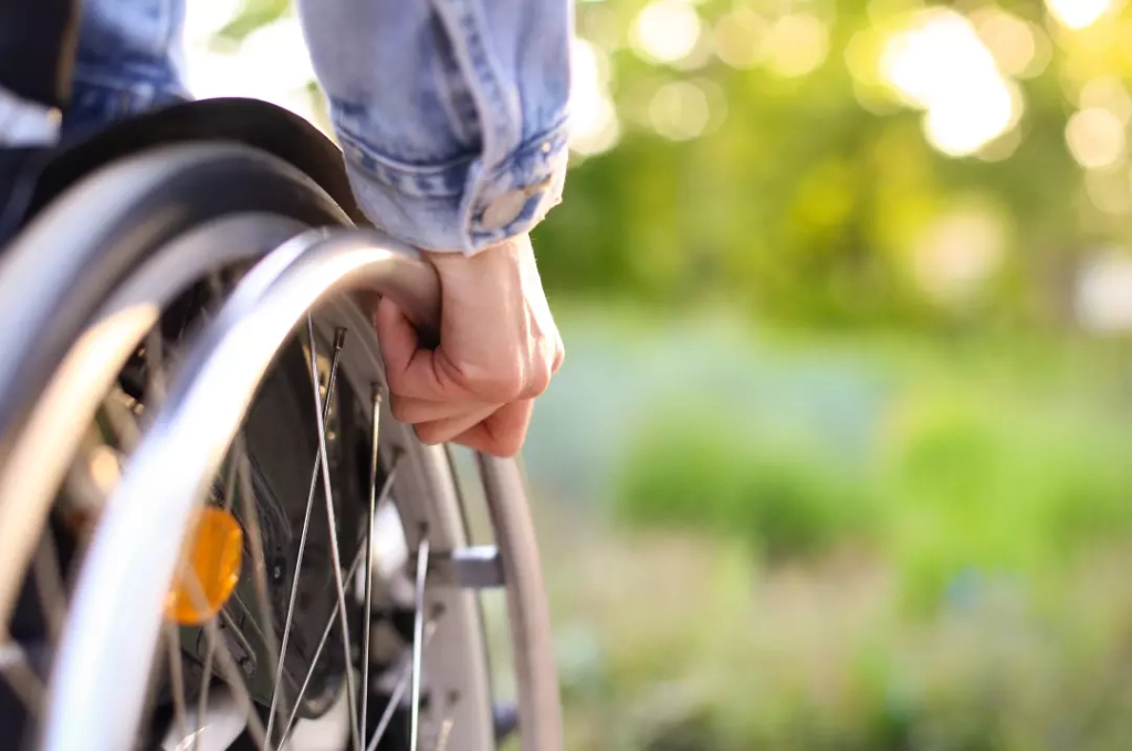 Hand holding a wheel of a wheelchair.
