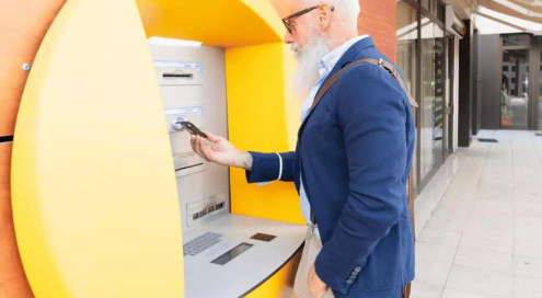 Senior man using an ATM machine to withdraw money.