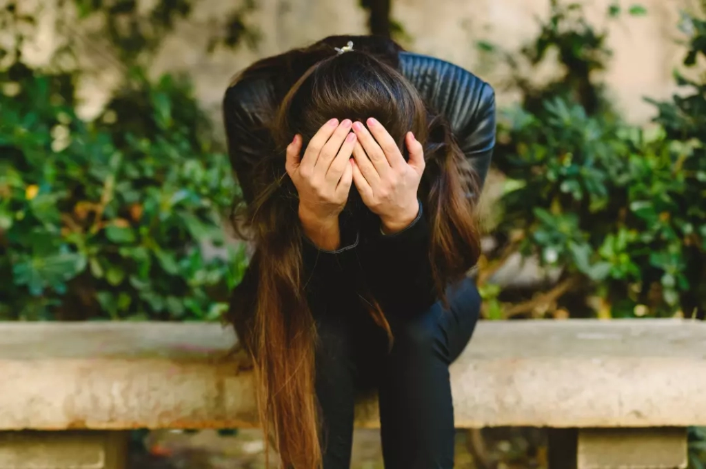 Young woman with depression holding her head in her hands.