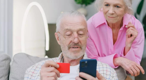 Senior couple using a card for online transaction.