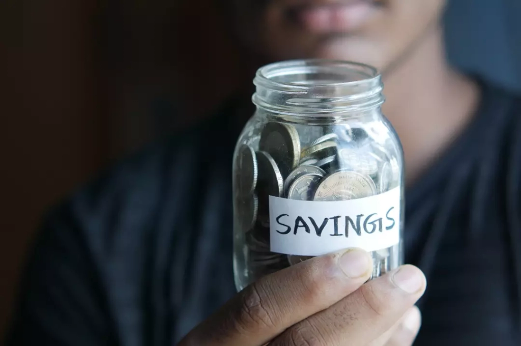 Man holding a savings jar filled with coins.
