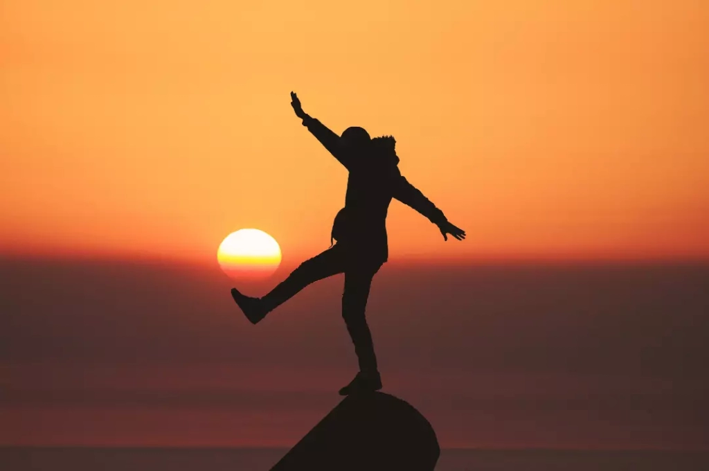 Silhouette of a man on top of a rock.