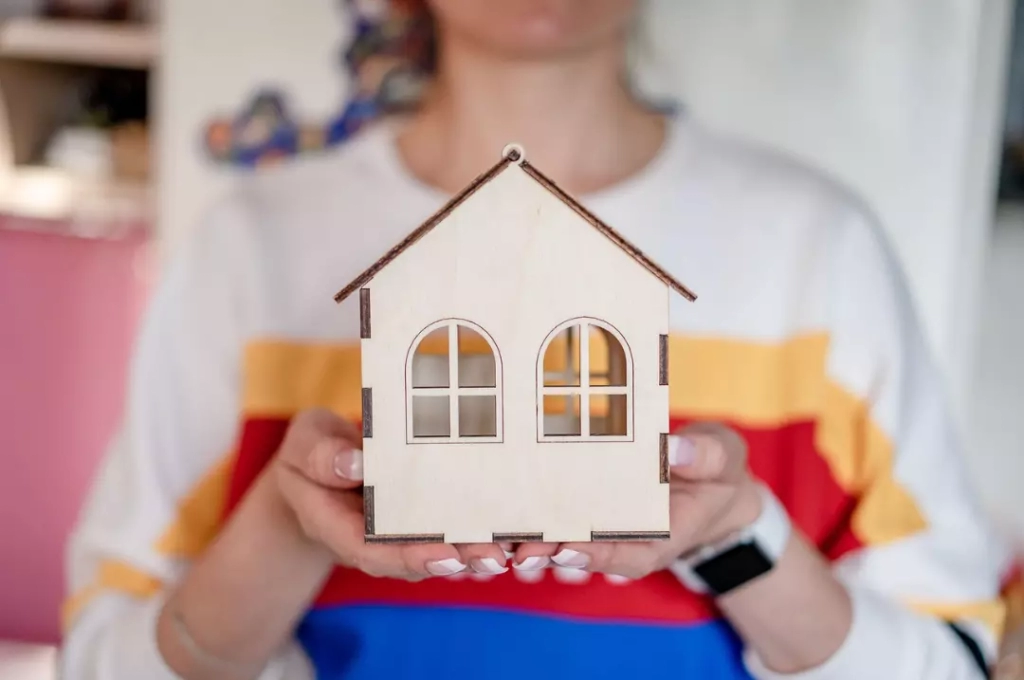 Woman holding a wooden miniature house.