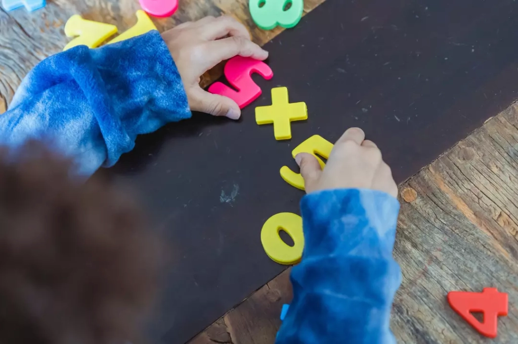 Kid solving math using toy numbers.