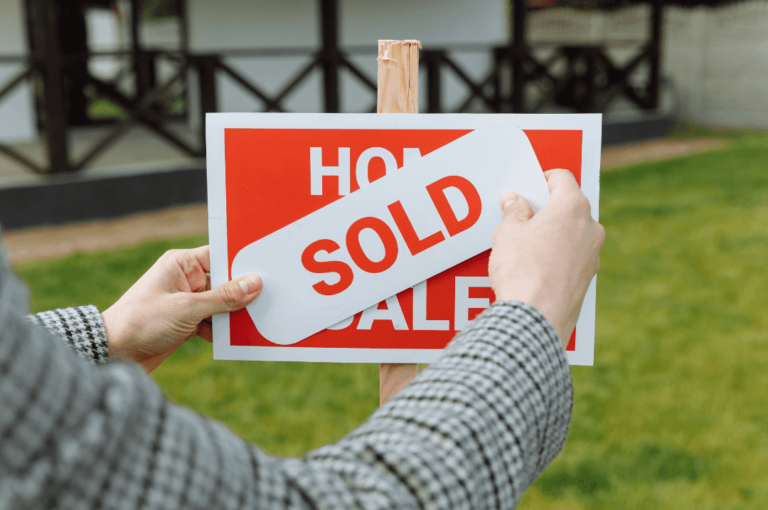 Real estate agent posting a sold sticker.