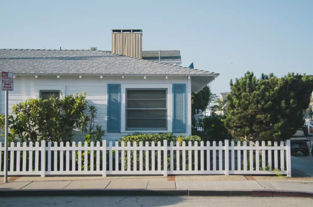 White and blue house with fence.