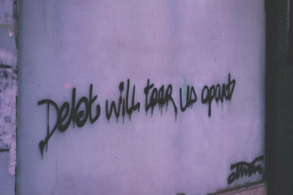 Graffiti on a wall that says debt will tear us apart.