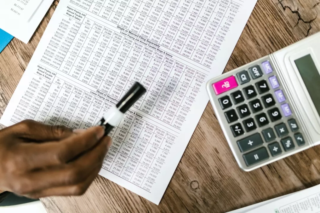 Person calculating with calculator and pen on paper to understand debt consolidation process.