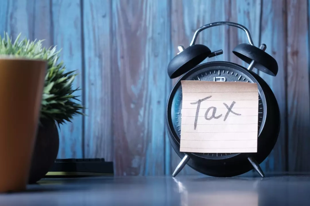 Tax word written on a note glued on an alarm clock.