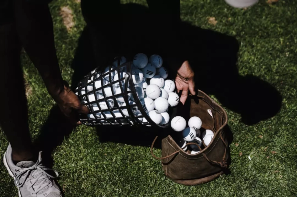 Transfering the golf balls from the basket to the bag.