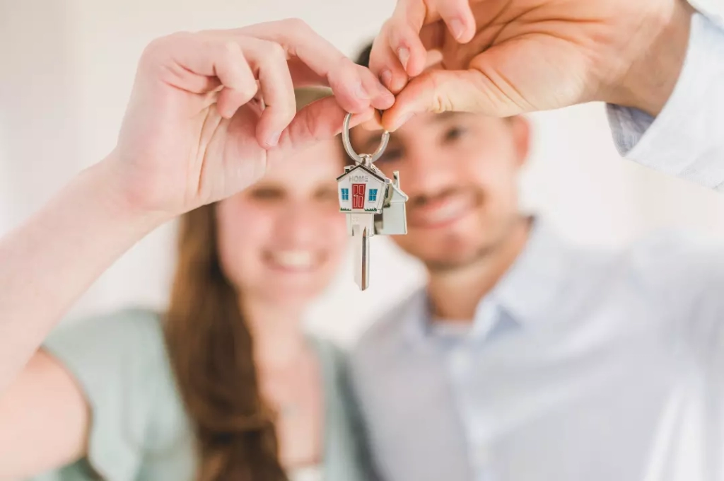Happy couple holding the key of their first property.
