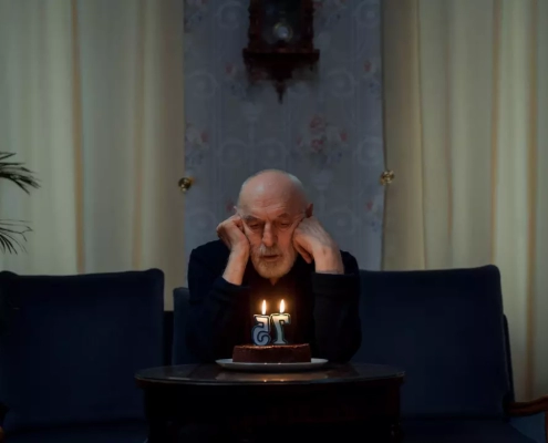 Lonely old man looking at his cake.