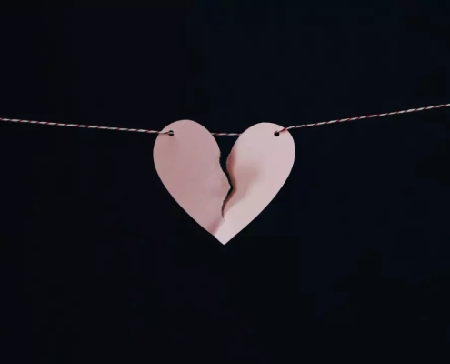 Broken paper heart hanging on a wire.