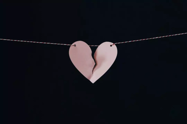Broken paper heart hanging on a wire.