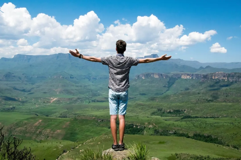 Man standing on a rock overlooking a mountain.